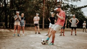 A group of people playing a fun outdoor soccer game wearing funny goggles.